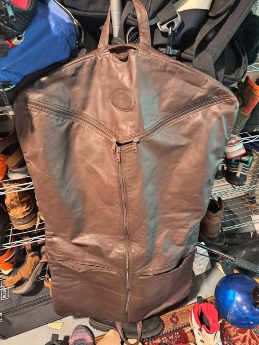 brown leather garment bag designed to protect hanging clothing during travel or